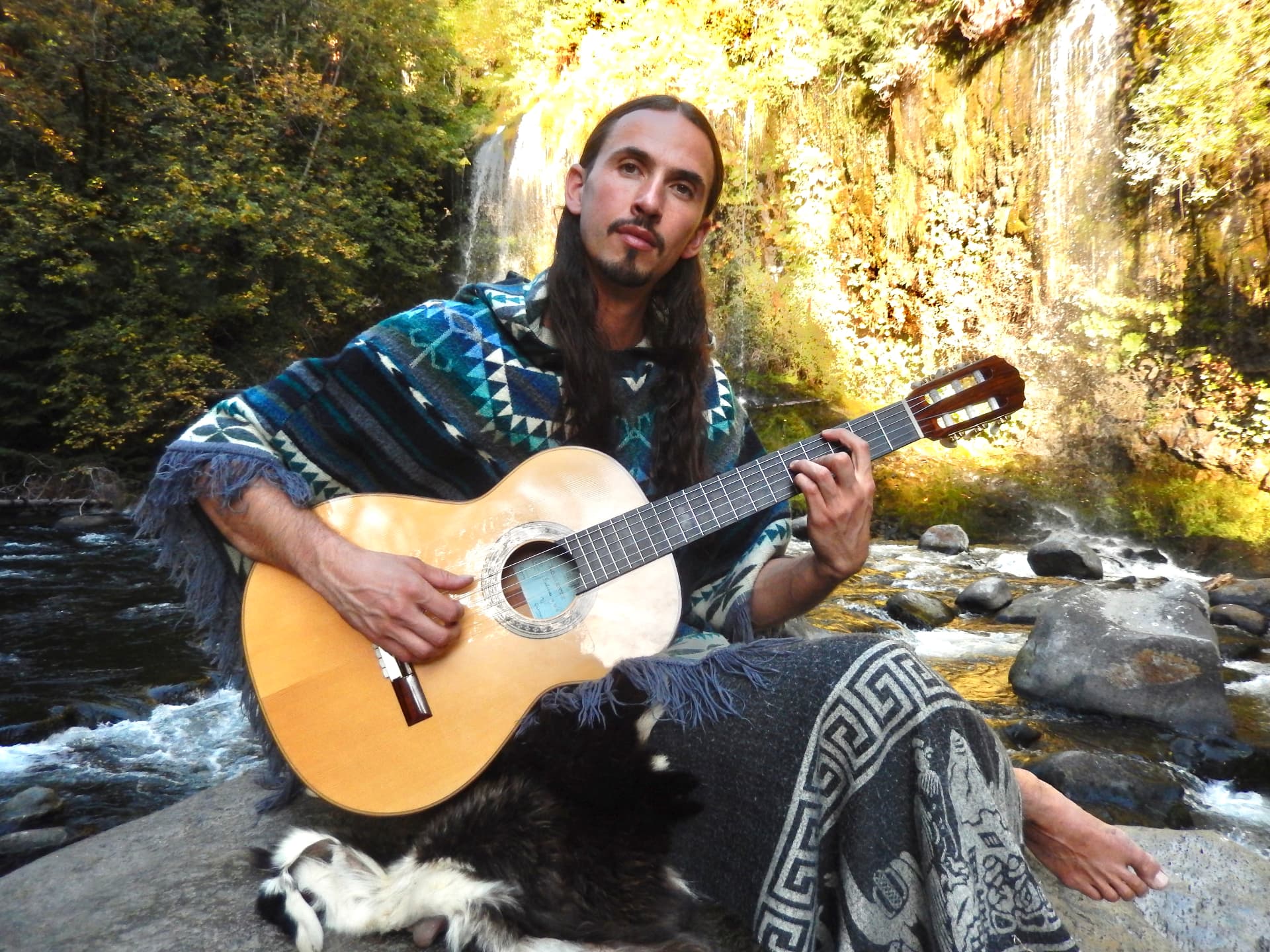 Cielo playing guitar beside a woodland waterfall