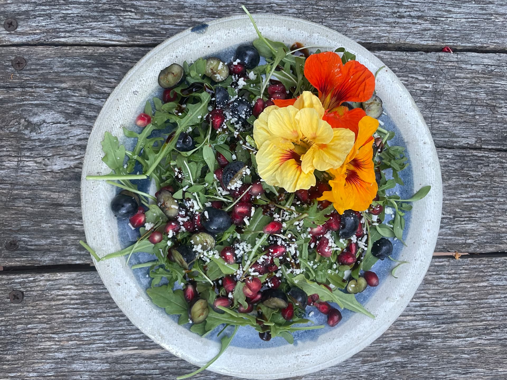 Fresh salad with blueberries, pomegranate and colorful edible flowers